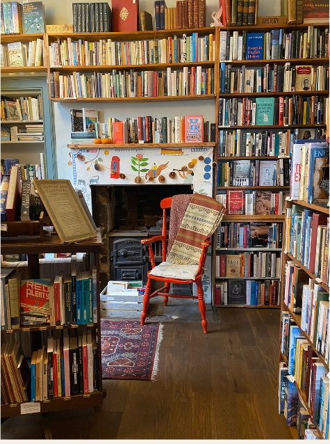 Interior of Tills Bookshop, Edinburgh, with bookshelves around a fireplace and red wooden chair